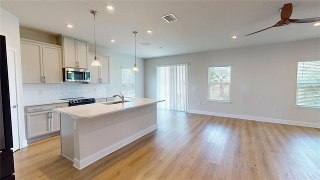 1002 Chelan Falls Dr, Deland, FL 32724 - kitchen with visible vents, a sink, stainless steel microwave, light wood-style floors, and black range with electric cooktop