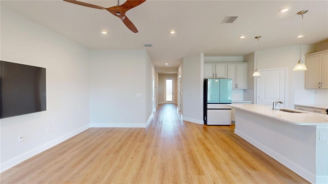 1002 Chelan Falls Dr, Deland, FL 32724 - kitchen with light countertops, a ceiling fan, a sink, freestanding refrigerator, and light wood-style flooring