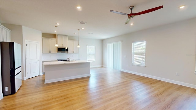 1002 Chelan Falls Dr, Deland, FL 32724 - kitchen with stainless steel microwave, freestanding refrigerator, a healthy amount of sunlight, and a ceiling fan
