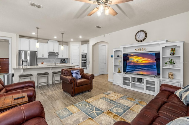 2901 Monaghan Dr, Ormond Beach, FL 32174 - living room with arched walkways, a ceiling fan, visible vents, and light wood-style flooring