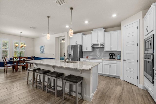 2901 Monaghan Dr, Ormond Beach, FL 32174 - kitchen with visible vents, stainless steel appliances, under cabinet range hood, and light wood-type flooring