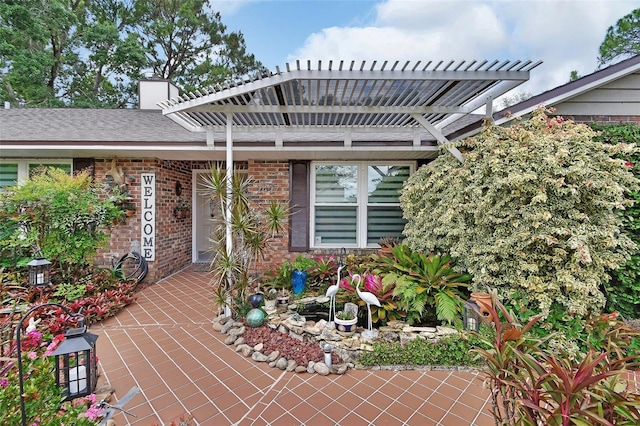 exterior space with brick siding, a pergola, a chimney, and a shingled roof