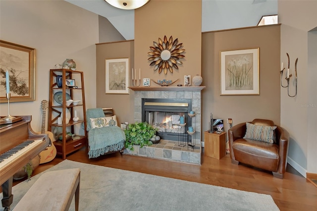 sitting room featuring vaulted ceiling, baseboards, wood finished floors, and a fireplace