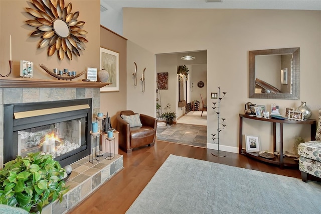 living room featuring visible vents, baseboards, wood finished floors, and a fireplace