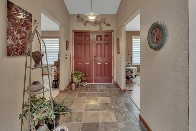 entrance foyer with baseboards and stone tile flooring
