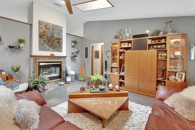 living area featuring vaulted ceiling with skylight, visible vents, and a tiled fireplace