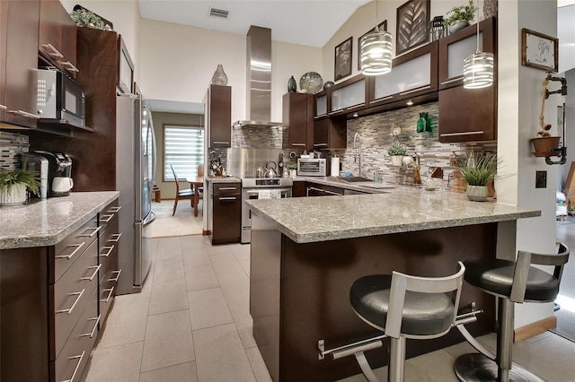 kitchen with tasteful backsplash, stainless steel appliances, wall chimney exhaust hood, a peninsula, and visible vents