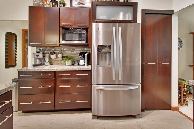 kitchen with backsplash, appliances with stainless steel finishes, light stone countertops, and light tile patterned flooring