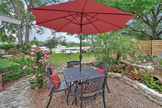 view of patio / terrace featuring a water view, outdoor dining area, and fence