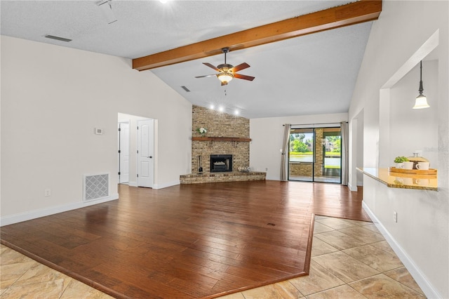 unfurnished living room with ceiling fan, a brick fireplace, vaulted ceiling with beams, visible vents, and hardwood / wood-style flooring
