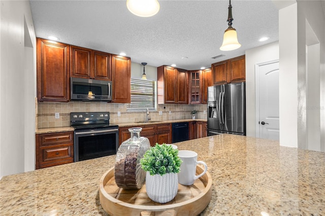 kitchen featuring decorative light fixtures, appliances with stainless steel finishes, glass insert cabinets, and a sink