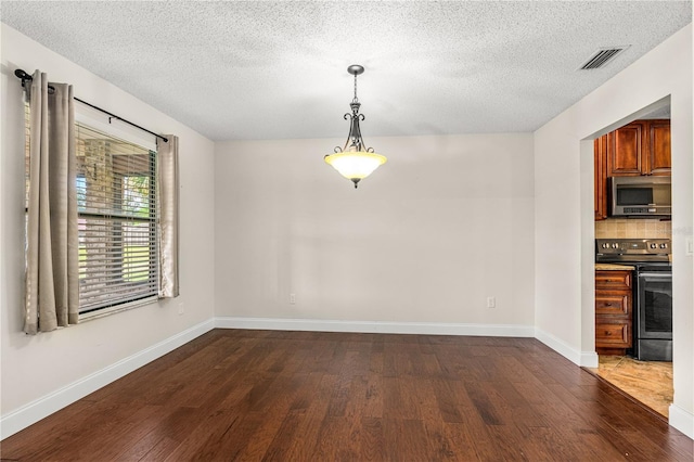 unfurnished dining area with baseboards, a textured ceiling, and dark wood finished floors