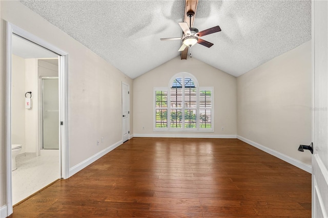 empty room featuring a textured ceiling, ceiling fan, vaulted ceiling with beams, and hardwood / wood-style floors