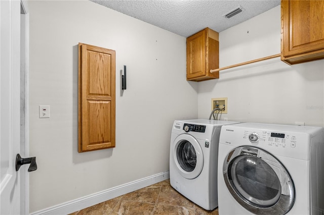 laundry area featuring visible vents, washing machine and dryer, baseboards, a textured ceiling, and cabinet space