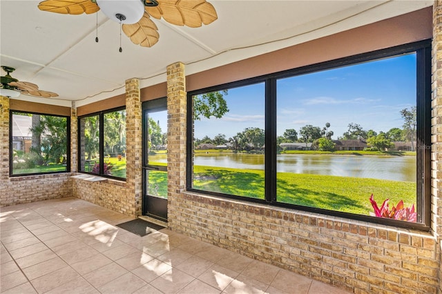 unfurnished sunroom featuring a water view, brick wall, and tile patterned flooring