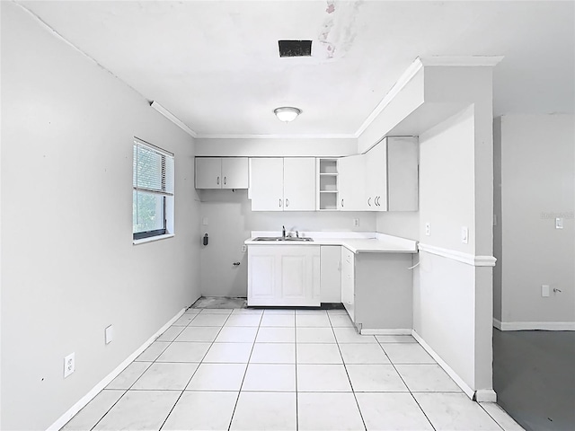 kitchen featuring light countertops, ornamental molding, a sink, baseboards, and white cabinetry