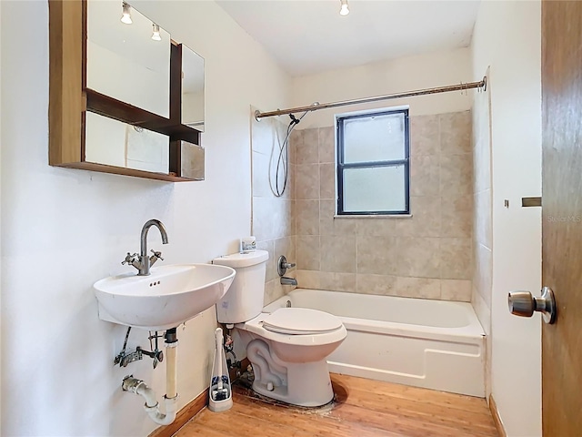 bathroom with wood finished floors, toilet, a sink, and shower / bathtub combination