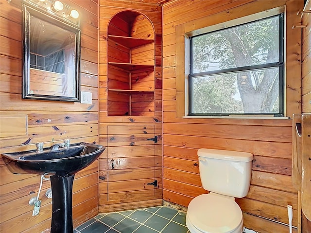 bathroom with tile patterned flooring, wood walls, and toilet
