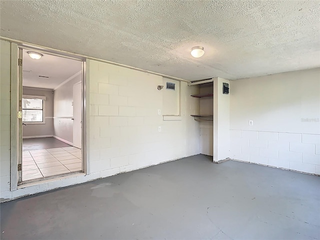 interior space with concrete block wall, concrete floors, a textured ceiling, and a closet