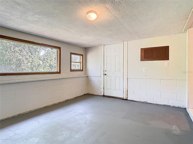 empty room featuring concrete floors, a textured ceiling, and concrete block wall