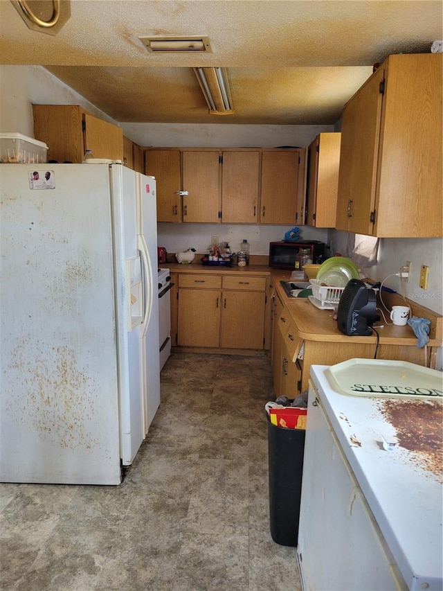 kitchen with light floors, light countertops, visible vents, white appliances, and a textured ceiling