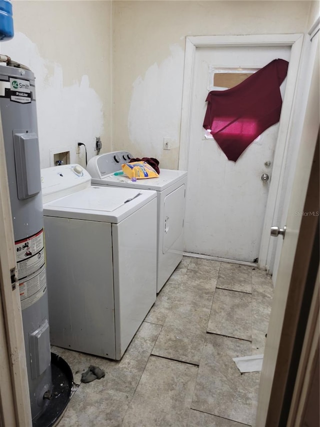 clothes washing area featuring water heater, washer and dryer, and laundry area