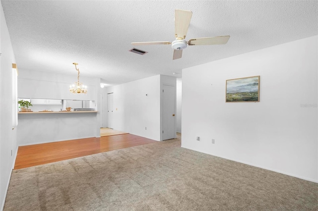 3 Fairway Ct, Deland, FL 32724 - unfurnished living room with a textured ceiling, visible vents, light colored carpet, and ceiling fan with notable chandelier