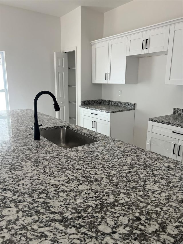 516 Model St, Daytona Beach, FL 32114 - kitchen with a sink, dark stone counters, and white cabinetry