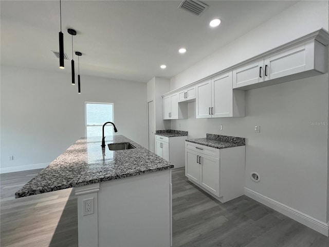 516 Model St, Daytona Beach, FL 32114 - kitchen featuring dark stone counters, light wood-style flooring, a center island with sink, recessed lighting, and white cabinetry
