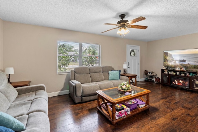living area with ceiling fan, baseboards, hardwood / wood-style floors, and a textured ceiling