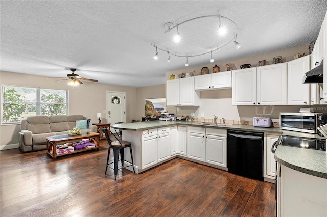 kitchen with a peninsula, a sink, white cabinetry, black dishwasher, and under cabinet range hood