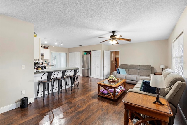 living room featuring a textured ceiling, a ceiling fan, baseboards, and dark wood-style flooring