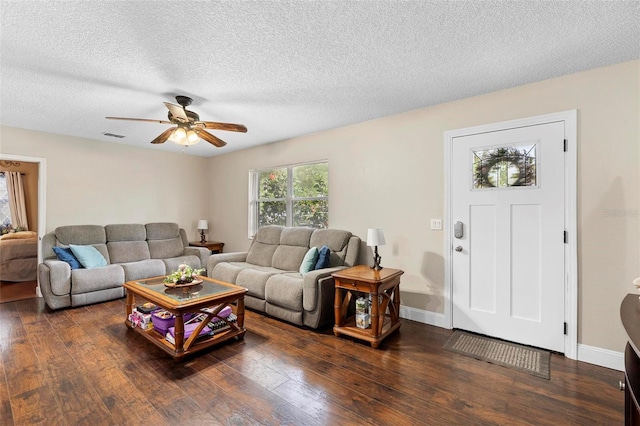 living area featuring dark wood finished floors, a ceiling fan, and a textured ceiling