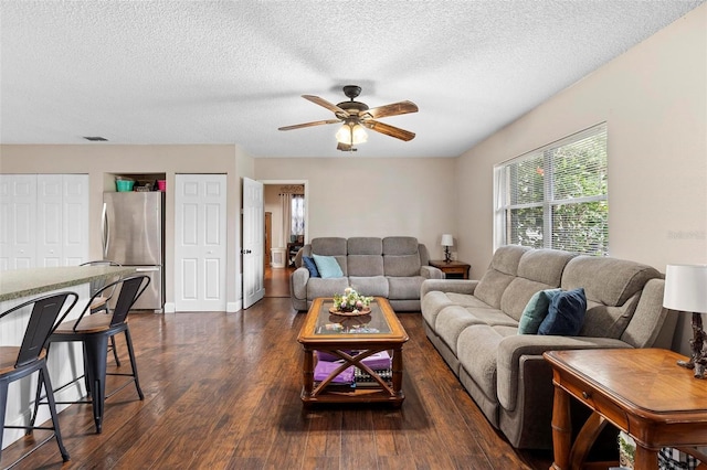 living area with dark wood-type flooring, a textured ceiling, a healthy amount of sunlight, and a ceiling fan