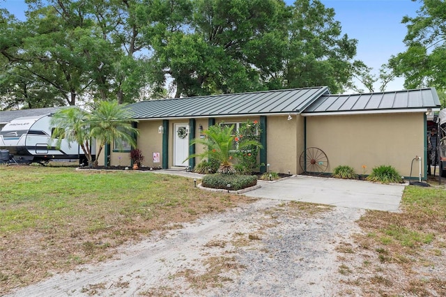 ranch-style house featuring stucco siding, driveway, a standing seam roof, and metal roof