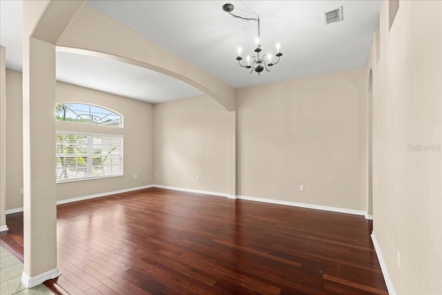 10 Zebrawood Ct, Palm Coast, FL 32164 - empty room with visible vents, baseboards, hardwood / wood-style flooring, arched walkways, and a notable chandelier