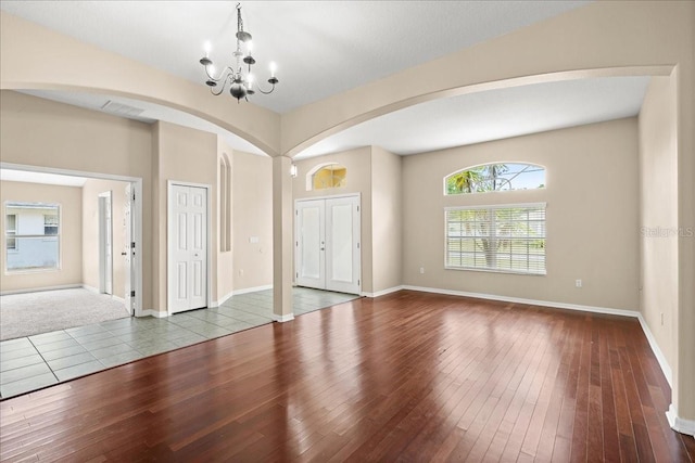 10 Zebrawood Ct, Palm Coast, FL 32164 - unfurnished room featuring visible vents, arched walkways, baseboards, wood-type flooring, and an inviting chandelier