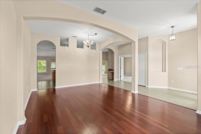 10 Zebrawood Ct, Palm Coast, FL 32164 - unfurnished living room with visible vents, baseboards, a notable chandelier, and hardwood / wood-style floors
