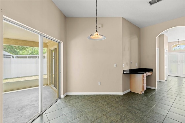 10 Zebrawood Ct, Palm Coast, FL 32164 - unfurnished dining area with arched walkways, baseboards, dark tile patterned floors, and visible vents