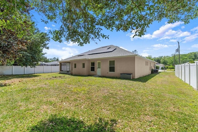 10 Zebrawood Ct, Palm Coast, FL 32164 - rear view of house with roof mounted solar panels, stucco siding, a lawn, and a fenced backyard