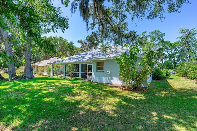 105 Riviera Estates Blvd, Ormond Beach, FL 32174 - rear view of house featuring stucco siding, a sunroom, and a lawn