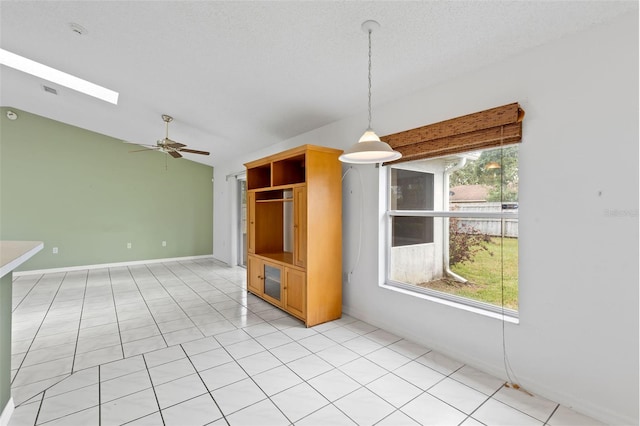 3214 Juniper Dr, Edgewater, FL 32141 - interior space with baseboards, a ceiling fan, vaulted ceiling with skylight, and light tile patterned floors