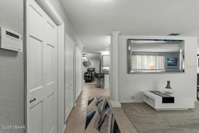 hall featuring baseboards, tile patterned flooring, visible vents, and decorative columns