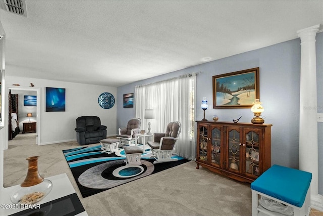 living room with carpet flooring, a textured ceiling, visible vents, and decorative columns