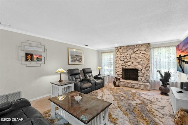 living area featuring a stone fireplace, tile patterned floors, baseboards, ornamental molding, and visible vents