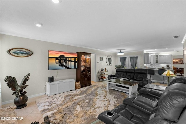 tiled living room with visible vents, baseboards, and crown molding