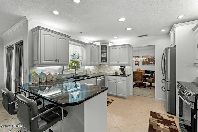 kitchen with stainless steel appliances, a peninsula, a sink, visible vents, and a breakfast bar area