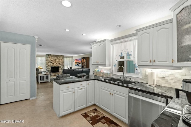 kitchen with a peninsula, stainless steel dishwasher, tasteful backsplash, and a sink