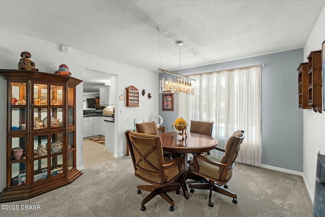 dining room with light colored carpet, baseboards, and a textured ceiling