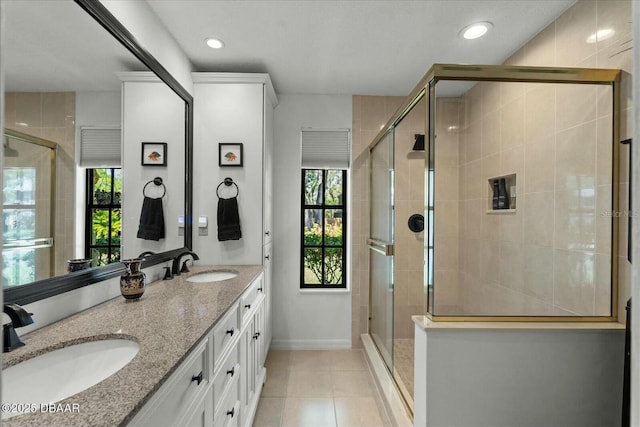 full bath with double vanity, tile patterned floors, a stall shower, and a sink